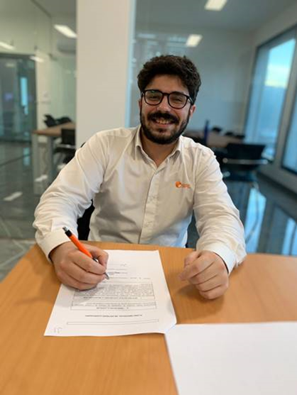 João Silva sorri para a fotografia durante a assinatura do contrato de trabalho.