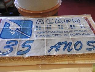 Fotografia do bolo de aniversário que contém o logotipo da ACAPO e por baixo 35 anos