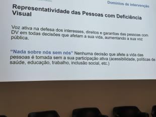 Projeção da tela de ecrã onde é possível ver-se um dos slides da apresentação da nossa Coordenadora dos Serviços de Reabilitação e Ação Social, com o título Representatividade das Pessoas com Deficiência Visual.