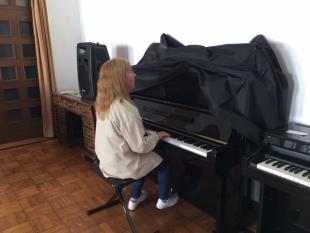 Sentada ao piano, uma das Beneficiárias que participou no Encontro, proporciona um momento musical.