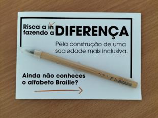 Lápis Infinito preso no postal alusivo à Deficiência Visual - Risca a indiferença, fazendo a diferença. Pela construção de uma sociedade mais inclusiva. Ainda não conheces o alfabeto Braille?