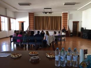 Fotografia tirada durante o Encontro de Pares onde é possível ver-se a mesa com o lanche que foi partilhado e, ao fundo, de costas, o grupo de Beneficiários que participou.